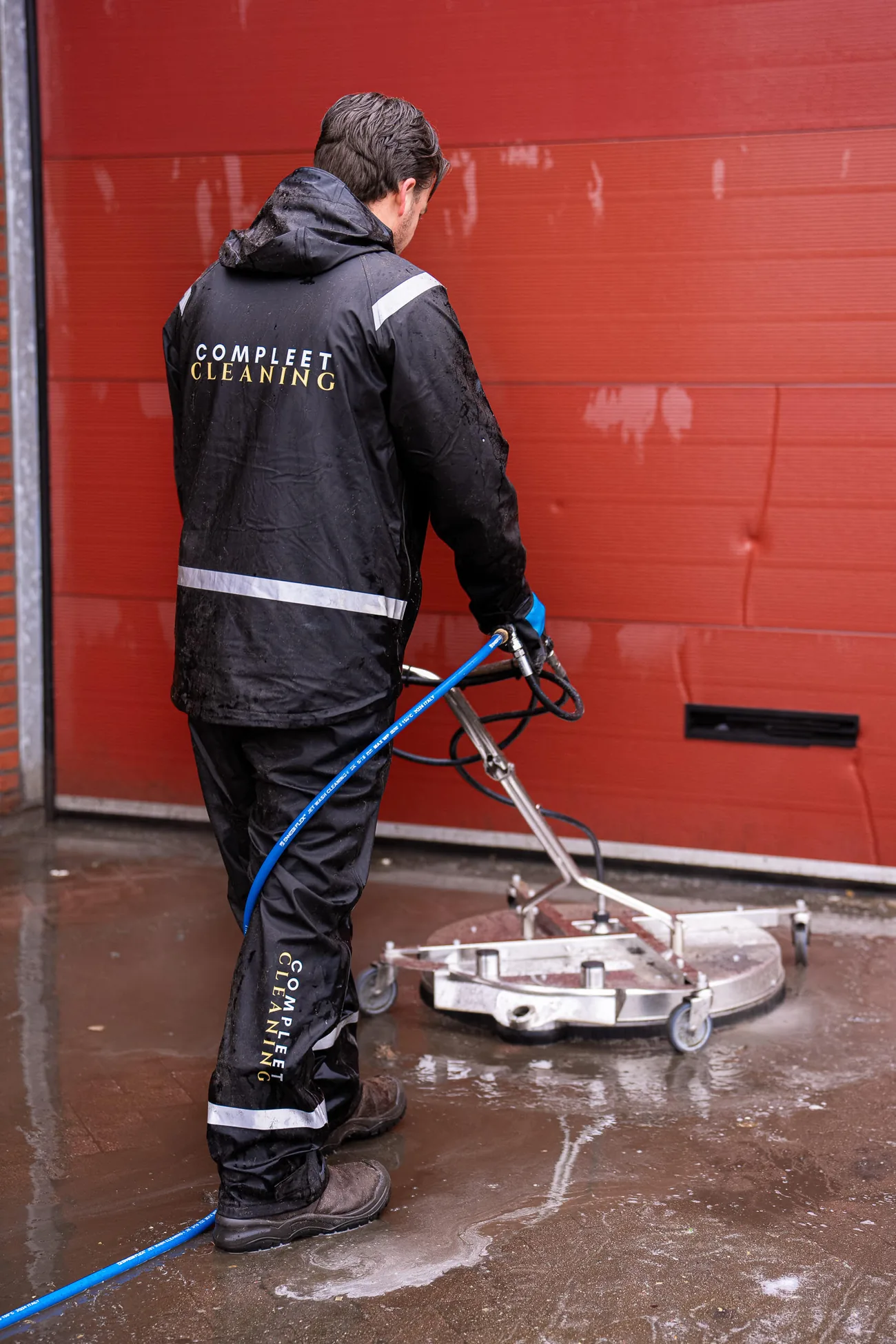 Medewerker van Compleet Cleaning reinigt een bedrijfspand met professionele hogedrukapparatuur
